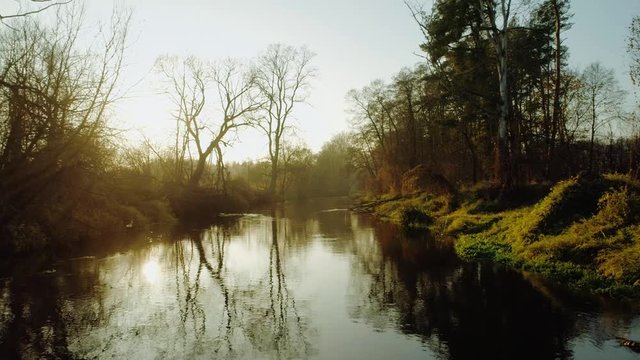 Scenic video of Polish river Wkra at sunset with gentle mist rising above water, almost fantasy scenery. Drone, aerial shot. Cinematic grading.