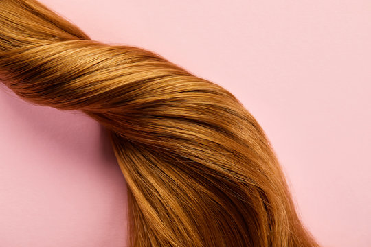 Top view of twisted brown hair on pink background