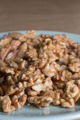 Many peeled walnuts on a blue plate close up still