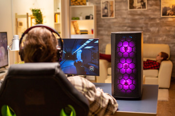 Back view of gamer male playing a shooter on his powerful PC computer late at night in the living room © DC Studio
