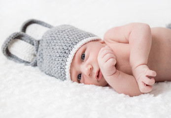 Cute little baby lies in a hare costume on a white background. newborn in a hat with ears on a white background