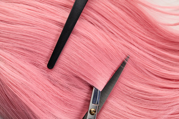 Top view of clip and scissors on colored pink hair on white background