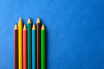 Multi colored crayons at blue background with copy space