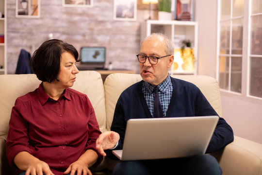 Elderly old couple using modern laptop to chat with their grandson