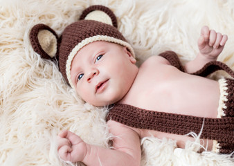 Cute little happy baby lies in a bear costume on a white background. newborn in a hat with ears on a white background