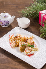 vareniki or dessert dumplings with apple and strawberry jam and cup of tea on wooden table