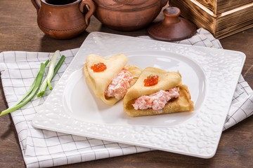 pancakes with cream cheese and smoked salmon on wooden table