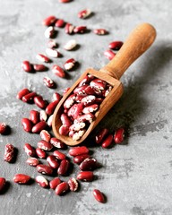 Raw beans in a wooden scoop on a gray background