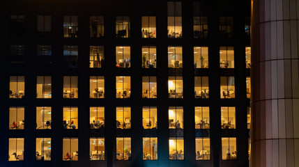 Office building exterior at night with interior lights on. Empty offices.