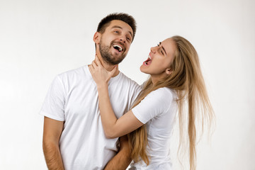 woman jokingly strangles man. angry woman shouting at her happy boyfriend on white background.