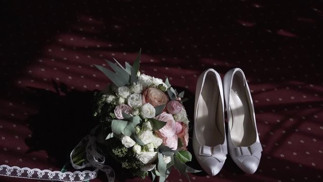 Bride's bouquet and bridesmaid's shoes in a hard light