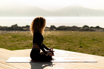 young woman meditating by peaceful sea