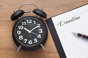 Deadline conceptual,book,pen and clock on wood