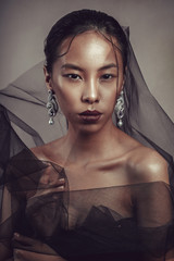 Beauty portrait of a beautiful asian girl with black transparent fabric.