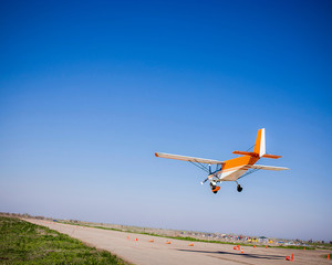 light single private orange plane in clear blue sky