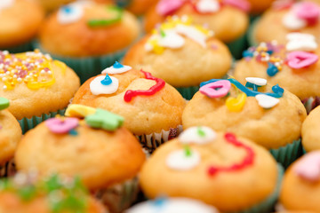 Close-up of a baking tray full of small homemade muffins with funny decoration ready for a children's birthday party