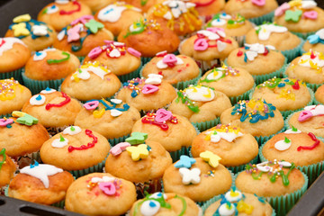 Close-up of a baking tray full of small homemade muffins with funny decoration ready for a children's birthday party