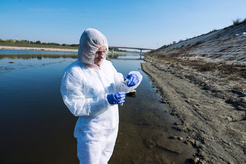 Female ecologist expert in protective clothes examining water quality and purity. Save the...