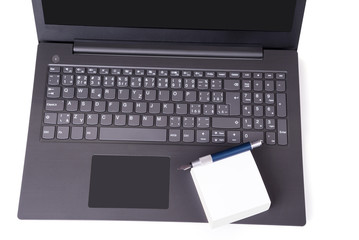 Modern slim laptop with pile of note paper and pair of glasses