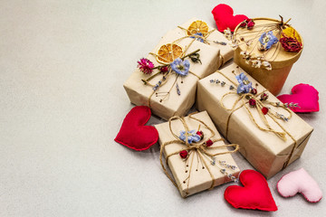 Zero waste gift concept. Valentine Day or Birthday eco friendly packaging. Festive boxes in craft paper with different organic decorations. Stone concrete background