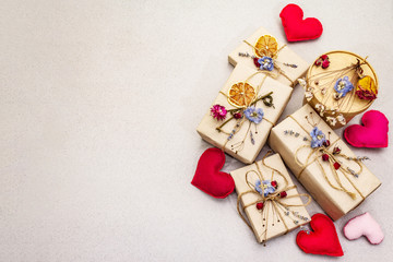 Zero waste gift concept. Valentine Day or Birthday eco friendly packaging. Festive boxes in craft paper with different organic decorations. Stone concrete background