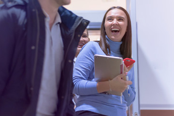 International group of students with going out from classroom  at university and resting after lecture. Happy friends studying together, spending free time on brake and smiling.