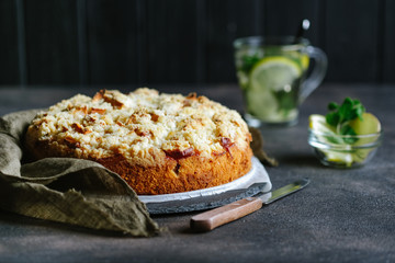 Homemade apple pie and fresh ginger tea with lemon slices, mint and honey on a dark background.