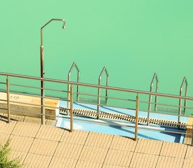 Shower and entering metal stairs of the swimming pool.