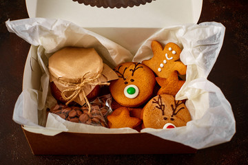 Delicious curly Christmas gingerbread, caramel in a jar covered with paper and tied with string, chocolate in a package in a gift box