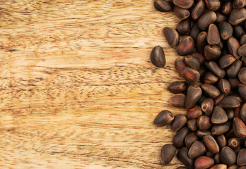 pine nuts in a wooden bowl on a brown background