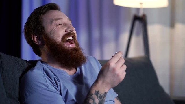 Laughing and happy adult man watching tm at home. 