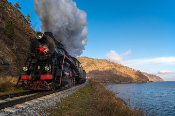 Fototapeta na wymiar An old steam train travels by rail along Lake Baikal