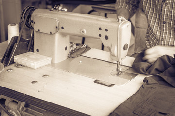 Filtered image Indian man hand on sewing machine and black fabric at Little India, Singapore