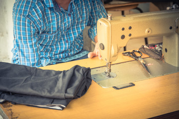 Indian man hand working with sewing machine and black fabric at Little India, Singapore