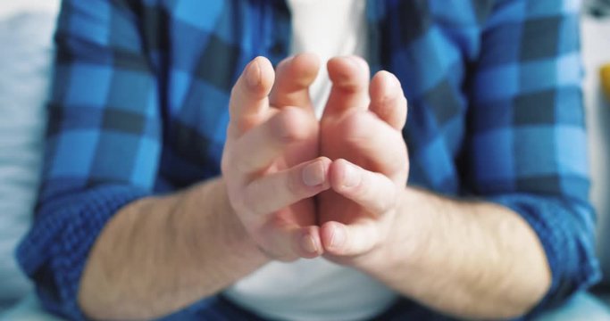 Close-up of wringing nervous man hands in blue shirts. The guy is very worried. Expectation. Waiting for an interview or hospital.