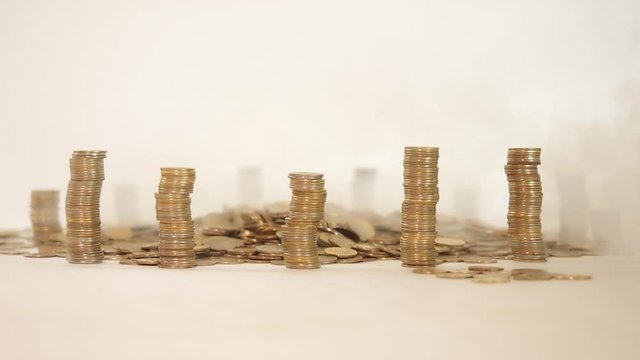 The concept of money. Columns of gold coins in the form of skyscrapers or Stonehenge. Close-up hands make up stacks of coins. Smoke. Garland.