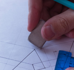 The man erases the diagram with an eraser. Design and create a project on a white sheet of paper...