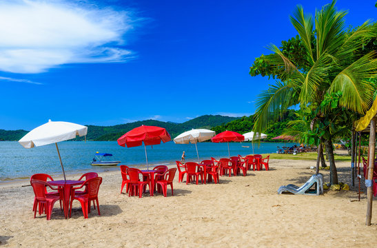 Jabaquara beach with umbrella and chairs in Paraty, Rio de Janeiro, Brazil. Paraty is a preserved Portuguese colonial and Brazilian Imperial municipality