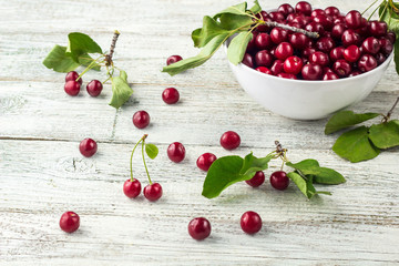 Fresh sweet cherries white bowl with leaves in water drops on wooden background