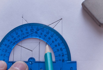 A man draws a diagram with a ruler, eraser and pencil. Design and create a project on a white sheet...