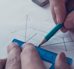 A man draws a diagram with a ruler, eraser and pencil. Design and create a project on a white sheet...
