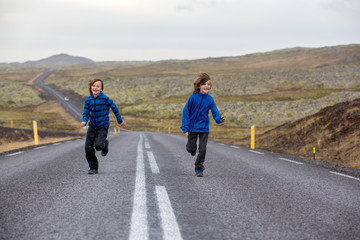 Obraz premium Kids running on an empty road in beautiful nature in Snaefellsjokull National Park in Iceland, autumntime