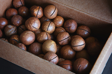 Unpeeled macadamia nuts are laying in the box