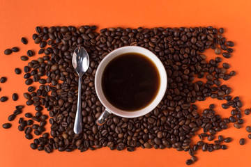 cup of aromatic coffee and coffee beans on an orange trendy background with space for text