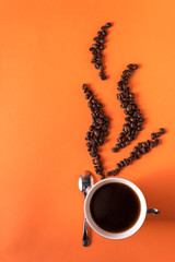 cup of aromatic coffee and coffee beans on an orange trendy background with space for text