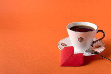 Obraz na płótnie Canvas cup of coffee and heart made of paper on orange trendy background with space for text