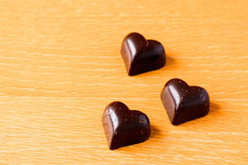 heart-shaped chocolates on the wooden background 