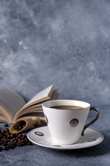  cup of coffee and coffee beans on a gray background and old books