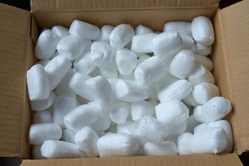 Smooth pieces of styrofoam in brown open postal parcel. It is a reliable way to transport items for...