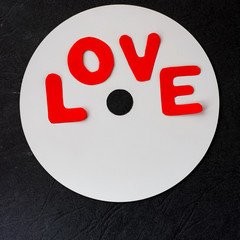 inscription love in red letters on the image of a musical disc made of white paper